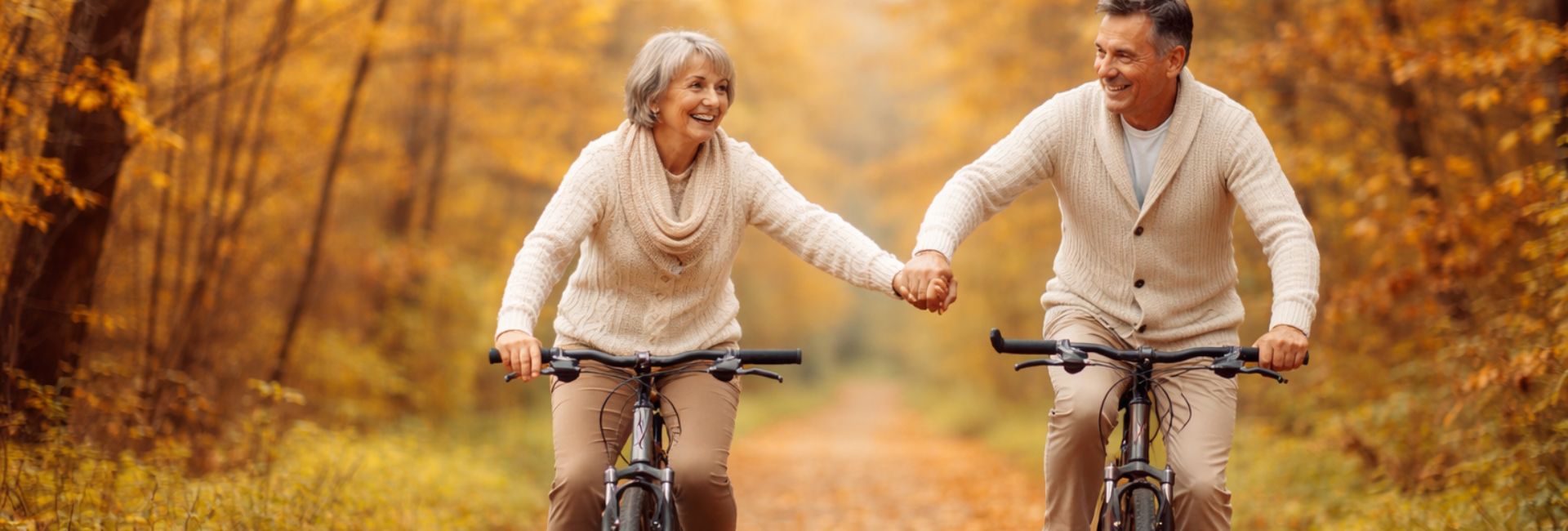 Active retired couple cycling together through autumn forest